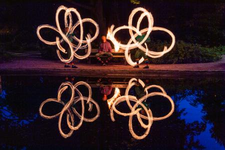 Kaksi tulikuviota ja niiden heijastukset lammen pinnasta.